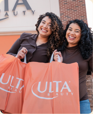 Two women holding Ulta Beauty bags outside a store