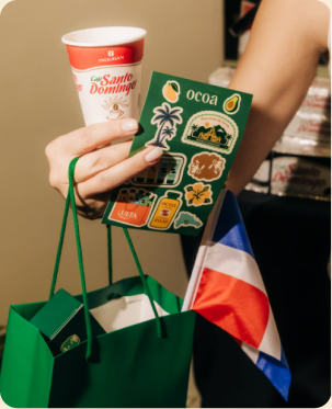 Hand holding coffee, Ocoa stickers, and a Dominican flag