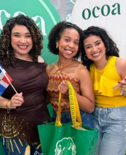 Three women with Ocoa tote bags and Dominican flags