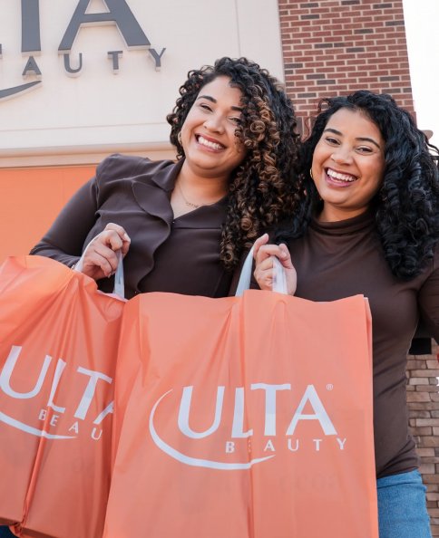Two women holding Ulta Beauty bags outside an Ulta store